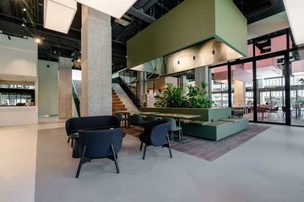 Moderne en open ingerichte lobby aan de Aert van Nesstraat met zitjes, planten en een trap naar de bovenverdieping.